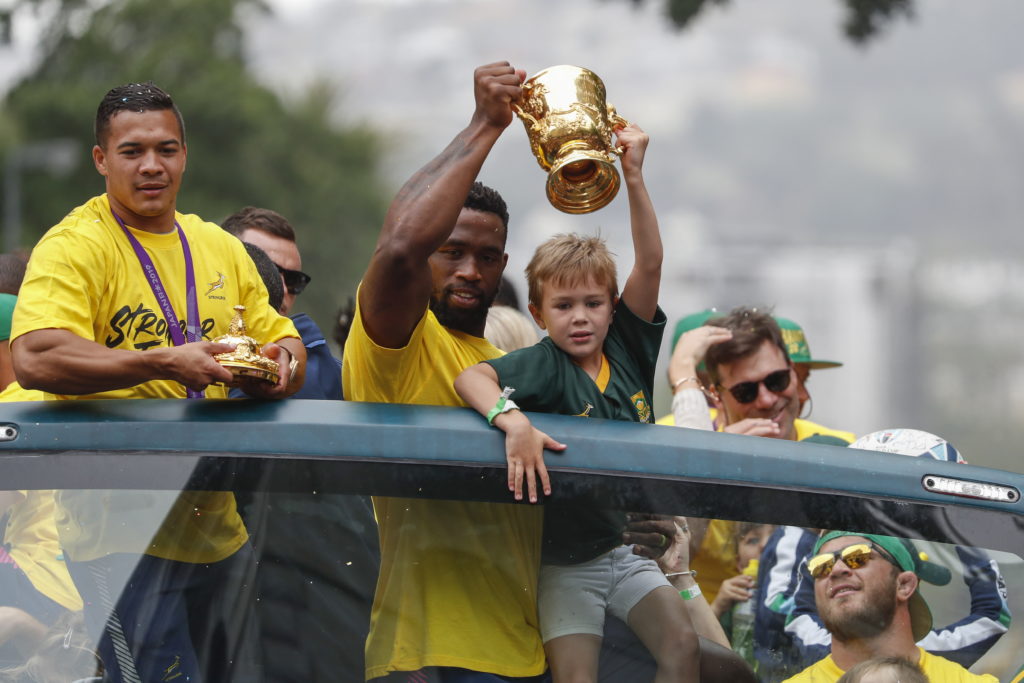 epa07988207 South African rugby captain Siya Kolisi (C) holds up the Webb Ellis Cup with a boy and players Cheslin Kolbe (L) and Duane Vermeulen (R) during a trophy tour in Cape Town, South Africa 11 November 2019. Tens of thousands of South Africans came out to see the Springboks finish their nation wide trophy tour in Cape Town after winning the Rugby World Cup. South Africa won the Webb Ellis Cup after defeating England 32-12 in the Rugby World Cup final played in Japan on 02 November 2019. EPA/NIC BOTHMA