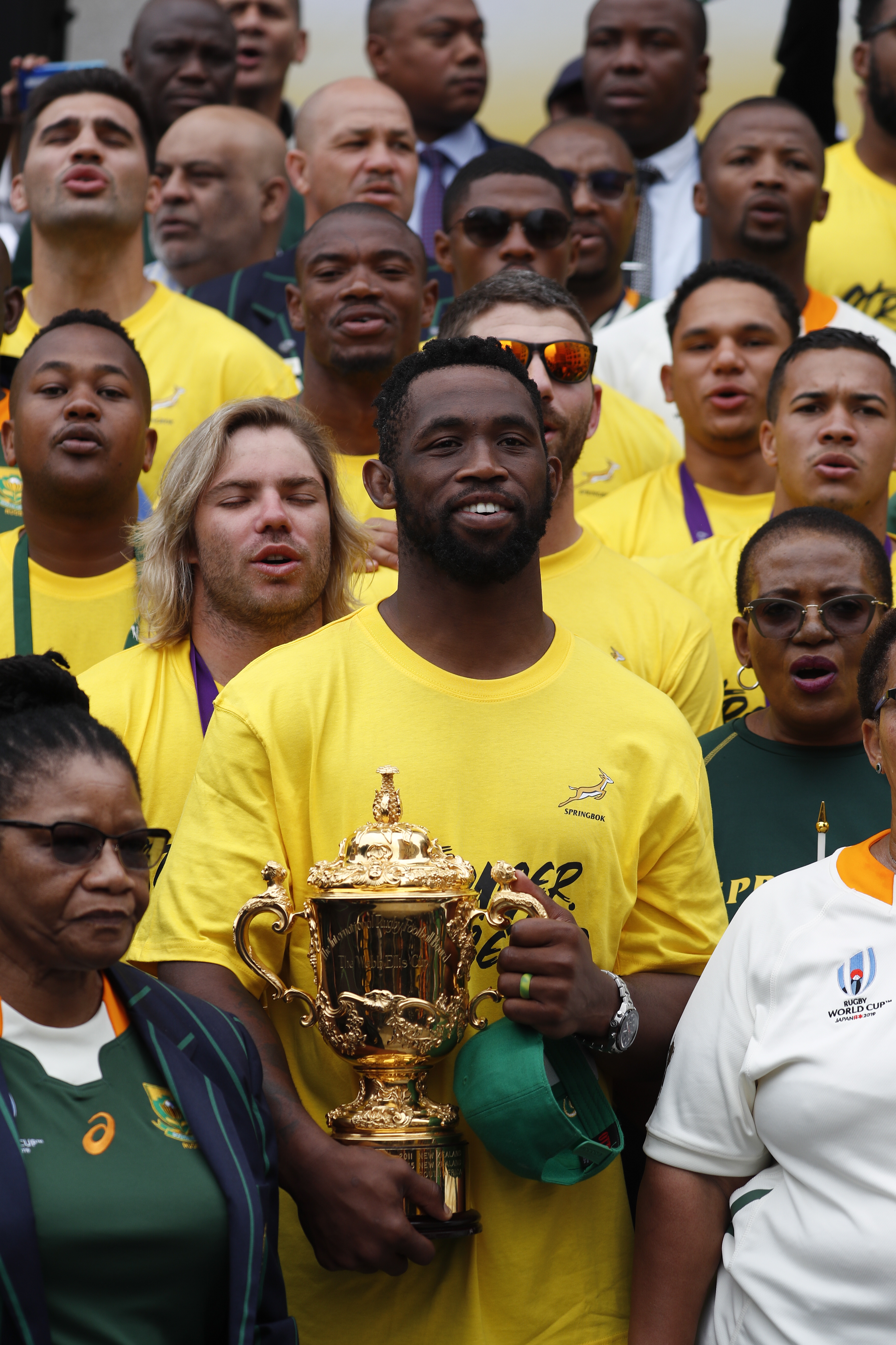 epa07988267 South African rugby captain Siya Kolisi (C) holds the Webb Ellis Cup as he poses for photographs with the team and speaker of parliament Thandi Modise (L) during a trophy tour visit to parliament in Cape Town, South Africa 11 November 2019. Tens of thousands of South Africans came out to see the Springboks finish their nation wide trophy tour in Cape Town after winning the Rugby World Cup. South Africa won the Webb Ellis Cup after defeating England 32-12 in the Rugby World Cup final played in Japan on 02 November 2019. EPA/NIC BOTHMA