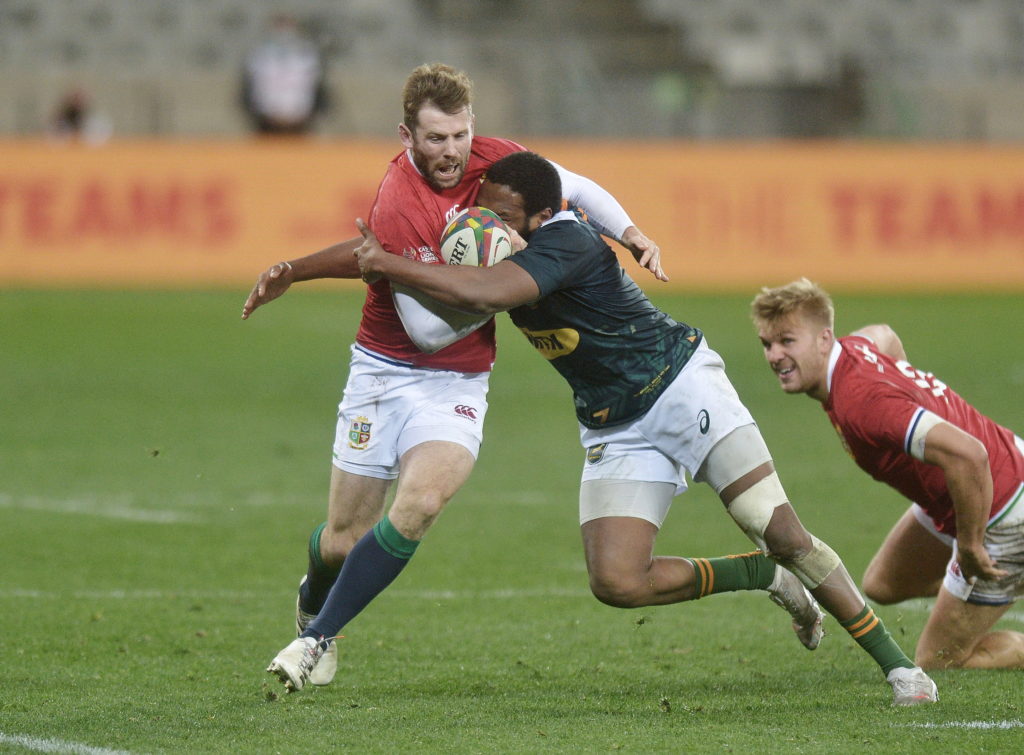 epa09344927 Chris Harris (L) of The British Lions is tackled by Lukhanyo Am (c) of the South African A team during the rugby union match against the British and Irish Lions at the Cape Town Stadium, Cape Town, South Africa, 14 July 2021.