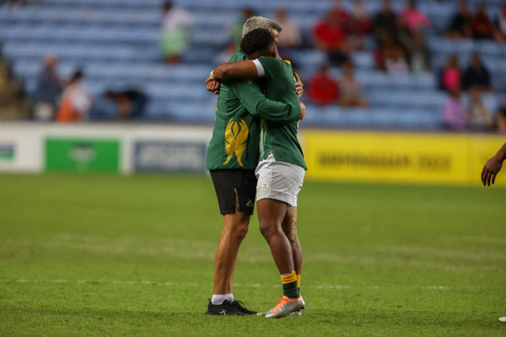 COVENTRY, ENGLAND - JULY 31: Neil Powell of South Africa hugs Angelo Davids after his team won the gold medal during the Rugby Sevens final match between South Africa and Fiji on day 3 of the 2022 Commonwealth Games at Coventry Stadium on July 31, 2022 in Coventry, England.
