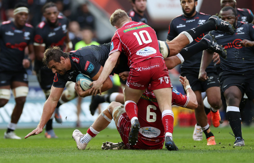 LLANELLI, WALES - MARCH 25: Eben Etzebeth of Cell C Sharks is tackled by Josh Macleod and Sam Costelow of Scarlets during the United Rugby Championship match between Scarlets and Cell C Sharks at Parc y Scarlets on March 25, 2023 in Llanelli, Wales.