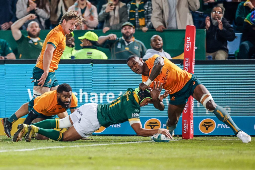 South Africa's wing Kurt-Lee Arendse (C) scores a try as Australia's wing Suliasi Vunivalu (R) tackles him during the Rugby Championship first round match between South Africa and Australia at Loftus Versfeld stadium in Pretoria on July 8, 2023. (Photo by PHILL MAGAKOE / AFP)